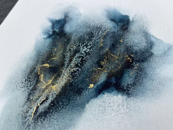 Tmavě modrý inkoust na bílém čtvercové, plátně. Abstraktní obrazec se zlatými akcent připomíná hvězdný prach.